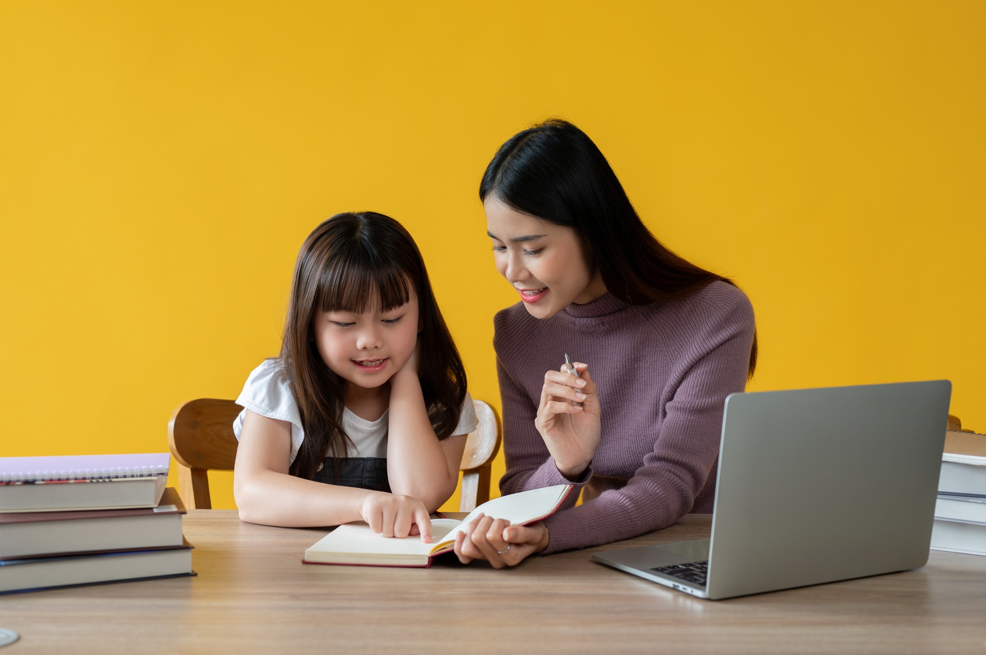 An adorable young Asian girl enjoys learning English with a female teacher.