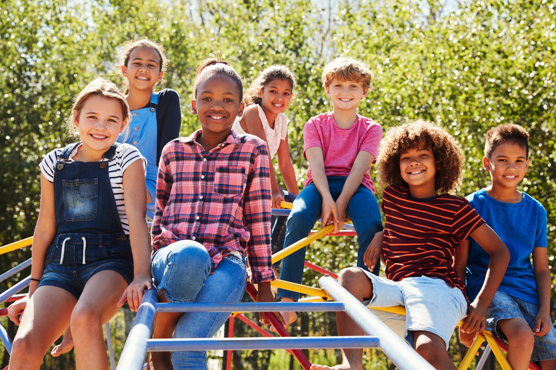 Pre-teen friends sitting on climbing frame in playground