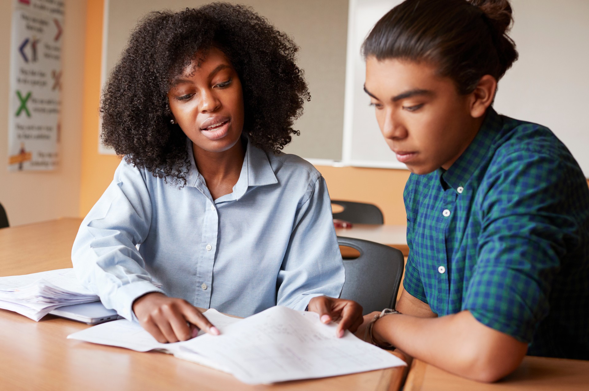 High School Tutor Giving Male Student One To One Tuition At Desk